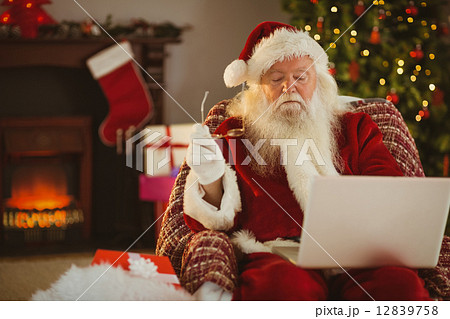 Santa claus using laptop on the armchair 12839758