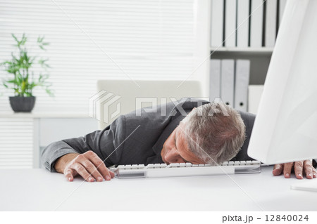 Exhausted businessman sleeping at his desk Exhausted businessman sleeping at his desk 12840024