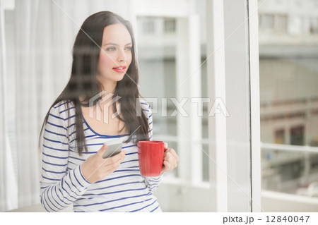 Pretty brunette holding mug and phone Pretty brunette holding mug and phone 12840047
