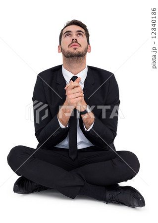 Businessman sitting praying and looking up 12840186