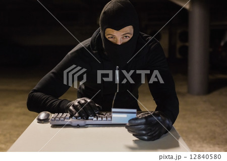 Burglar shopping online with laptop Burglar shopping online with laptop 12840580
