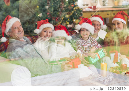 Three generation family opening christmas gifts on couch Three generation family opening christmas gifts on couch 12840859