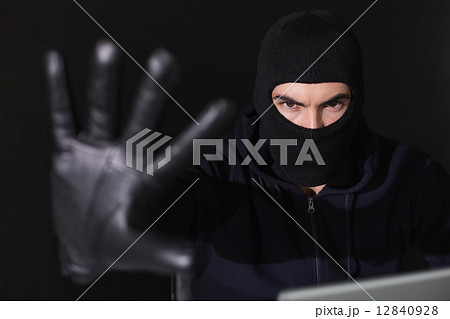 Hacker in balaclava gesturing and looking at camera Hacker in balaclava gesturing and looking at camera 12840928