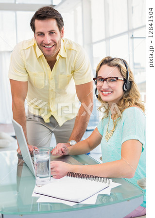 Portrait of a woman wearing headphone and her colleague 12841504