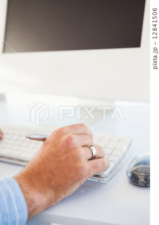 Close up of a hand holding pencil and typing on keyboard 12841506