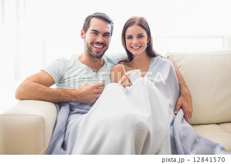 Cute couple relaxing on couch under blanket 12841570