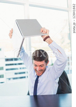 Angry businessman throwing his laptop Angry businessman throwing his laptop 12841662