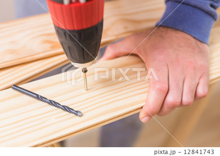 Casual man drilling hole in plank 12841743