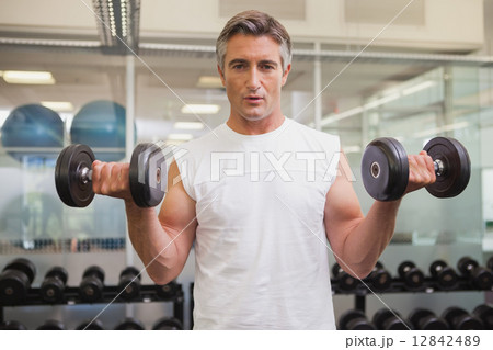 Fit man lifting heavy black dumbbells 12842489