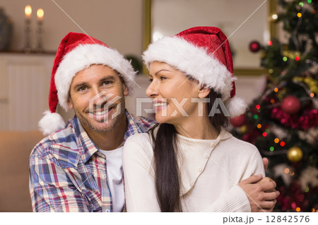 Festive couple in santa hat hugging on the couch Festive couple in santa hat hugging on the couch 12842576