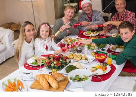 Smiling family pulling christmas crackers at the dinner table Smiling family pulling christmas crackers at the dinner table 12842588