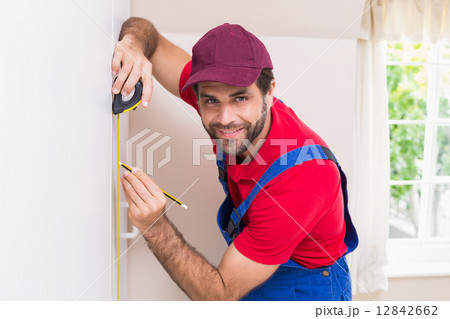 Construction worker using measuring tape 12842662