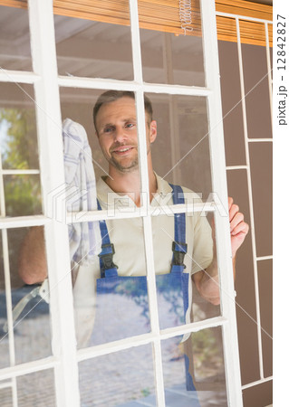 Handyman cleaning the window and smiling 12842827