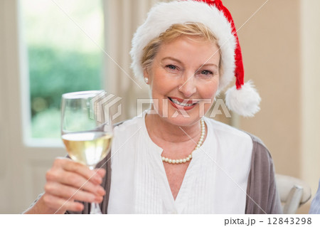 Smiling mature woman in santa hat toasting with white wine Smiling mature woman in santa hat toasting with white wine 12843298