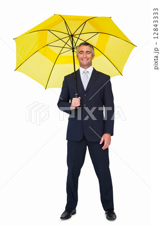 Smiling businessman under yellow umbrella 12843333