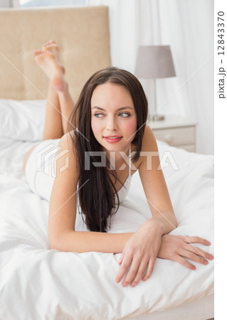 Pretty brunette lying on her bedの写真素材 [12843370] - PIXTA