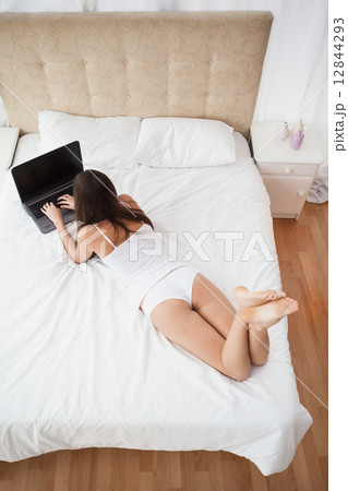 Pretty brunette using laptop on bed 12844293