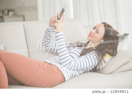 Pretty brunette listening to music on the couch 12844811