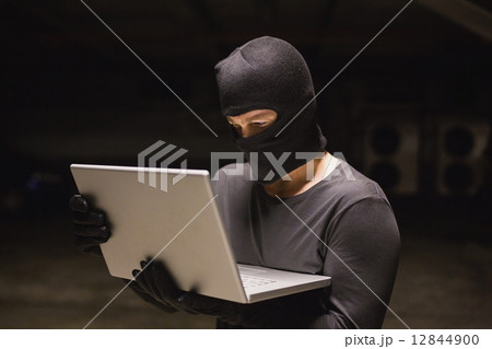 Hacker using laptop to steal identity 12844900