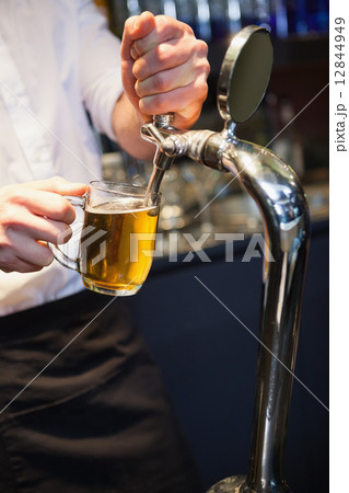 Handsome barkeeper pulling a pint of beer Handsome barkeeper pulling a pint of beer 12844949