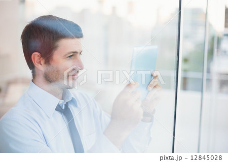 Businessman using tablet seen through window 12845028