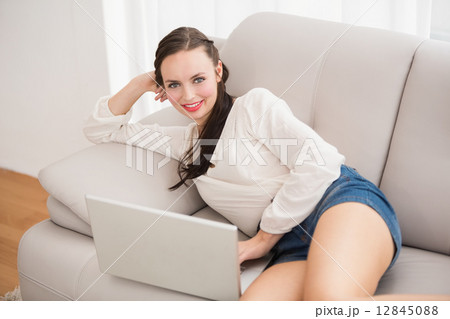 Pretty brunette using laptop on the couch Pretty brunette using laptop on the couch 12845088