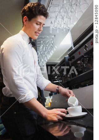 Barista pouring milk into cup of coffee Barista pouring milk into cup of coffee 12845090