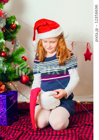Little girl near the Christmas tree with gifts and toys 12856696