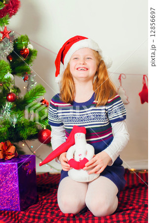 Little girl near the Christmas tree with gifts and toys 12856697