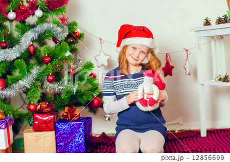 Little girl near the Christmas tree with gifts and toys 12856699