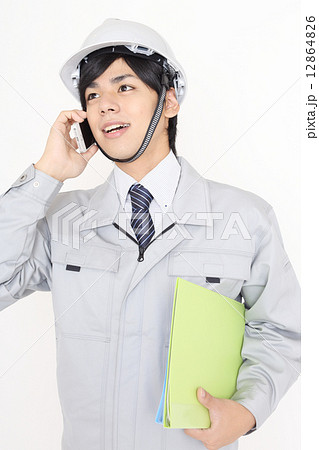 携帯電話をかける作業服を着た男性 12864826