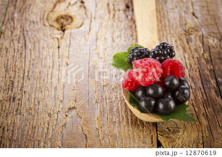 fresh berries in wooden spoon on wooden table 12870619