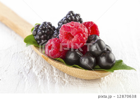 forest berries in wooden spoon on white wooden table 12870638