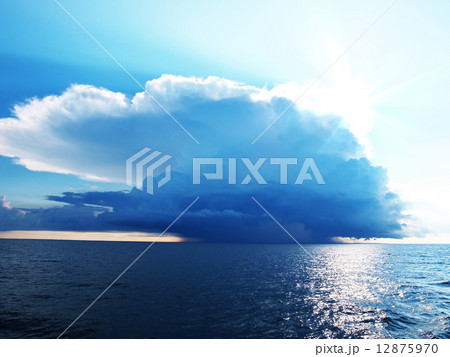 Bright blue sky with stormy clouds over a calm sea Bright blue sky with stormy clouds over a calm sea 12875970