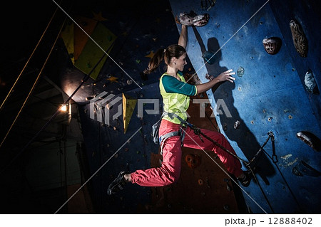 Young woman practicing rock-climbing on a rock wall indoors 12888402
