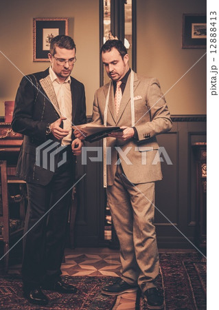 Tailor and client choosing cloth and buttons for custom made suit 12888413