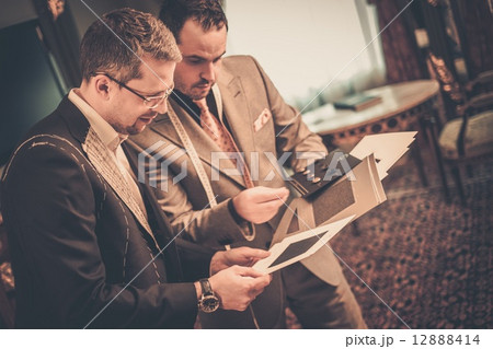 Tailor and client choosing cloth and buttons for custom made suit 12888414