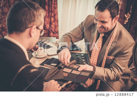 Tailor and client choosing cloth and buttons for custom made suit 12888417