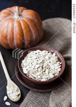 Bowl with toasted pumpkin seeds and wooden spoon 12888503