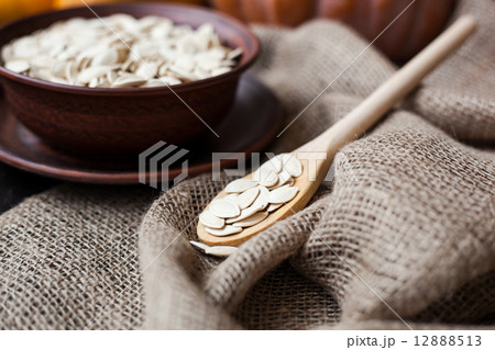 Bowl with toasted pumpkin seeds and wooden spoon 12888513