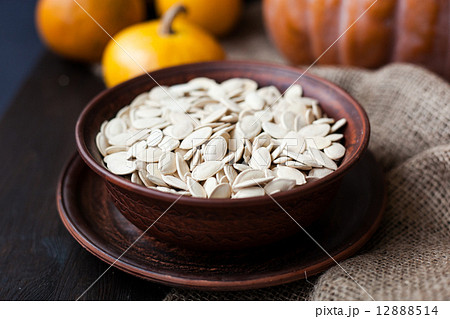 Bowl with toasted pumpkin seeds and wooden spoon 12888514