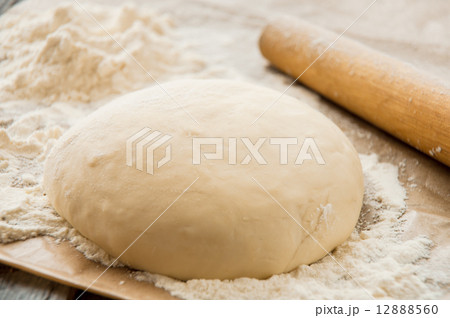 wooden rolling pin with freshly prepared dough for pizza wooden rolling pin with freshly prepared dough for pizza 12888560