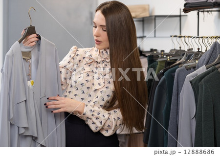 Young woman choosing clothes on a rack in a showroom Young woman choosing clothes on a rack in a showroom 12888686
