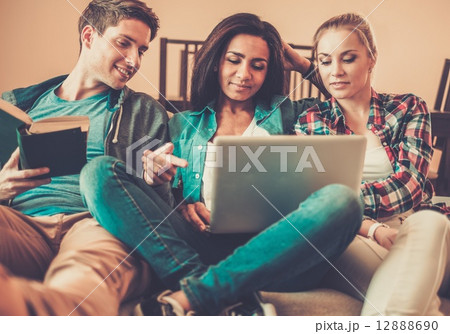 Three young students preparing for exams in home interior 12888690