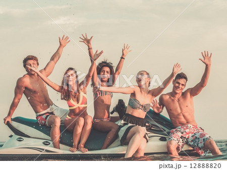 Group of happy multi ethnic friends sitting on a jet ski 12888820