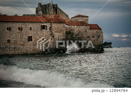 stone citadel on high cliff at late evening in stormy sea stone citadel on high cliff at late evening in stormy sea 12894764