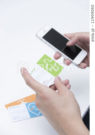 診察券をもって電話予約をする男性手元 12909060