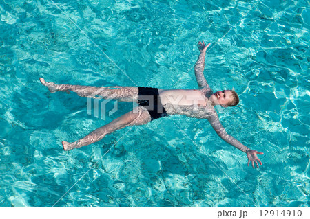 Teenager has a rest on turquoise transparent water of ocean.. 12914910
