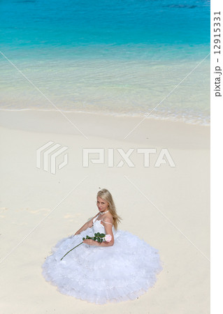 The young beautiful woman in a dress of the bride sits on sand at sea edge 12915331