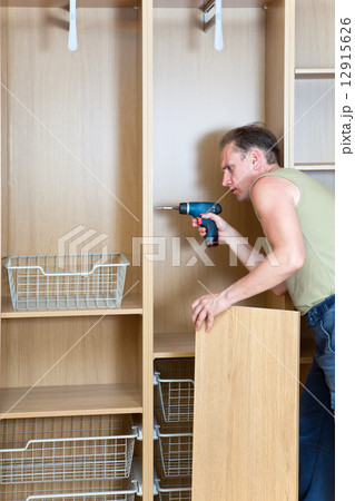 The man is engaged in repair and furniture assemblage 12915626